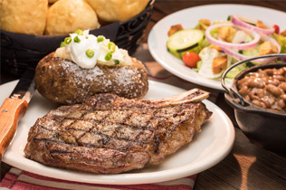 photograph of a plated ribeye steak and baked potato